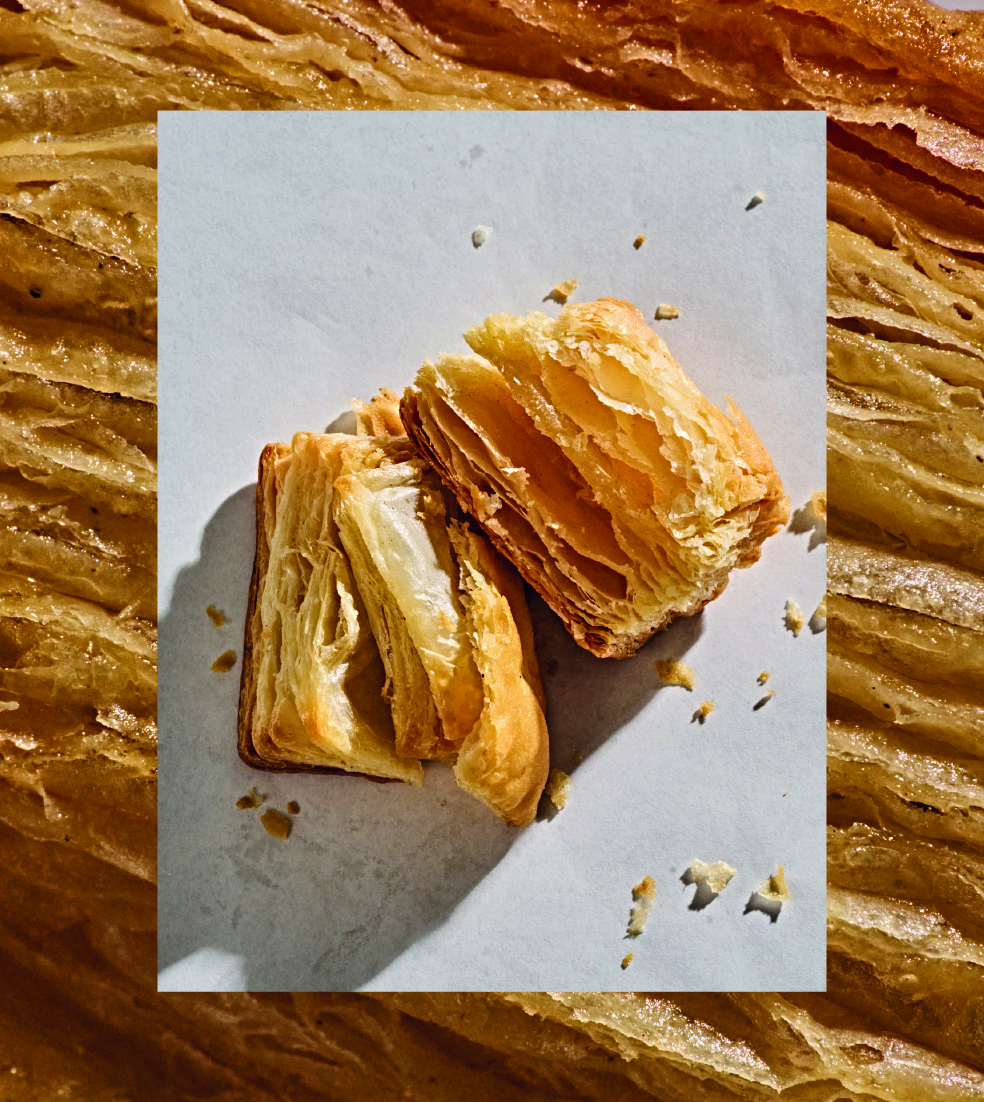 Blatterteig-Quadrate, auseinandergebrochen, auf weissen Hintergrund; umgeben von Textur des Blatterteigs.